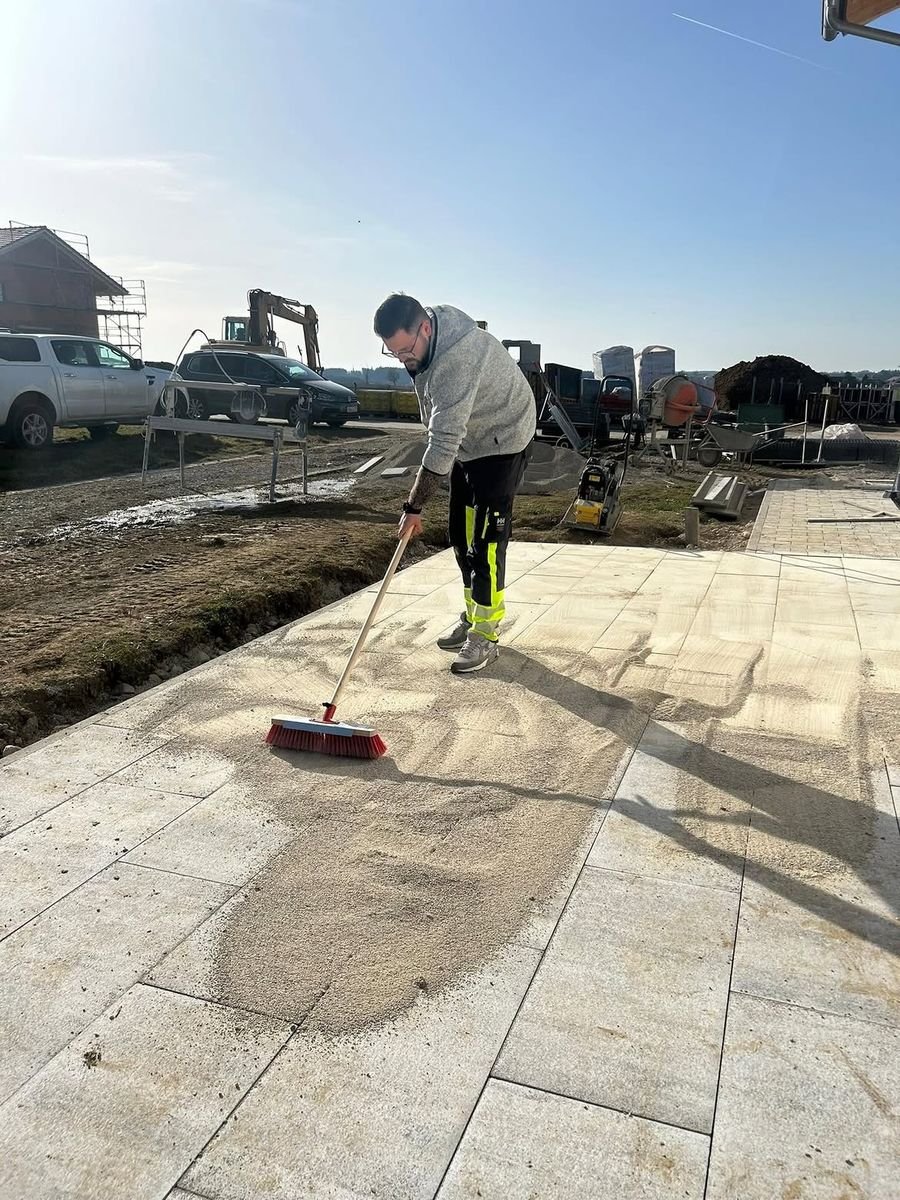 Hausmeisterservice Mayer beim Einkehren von Fugensand auf einer neuen Terrassenfläche